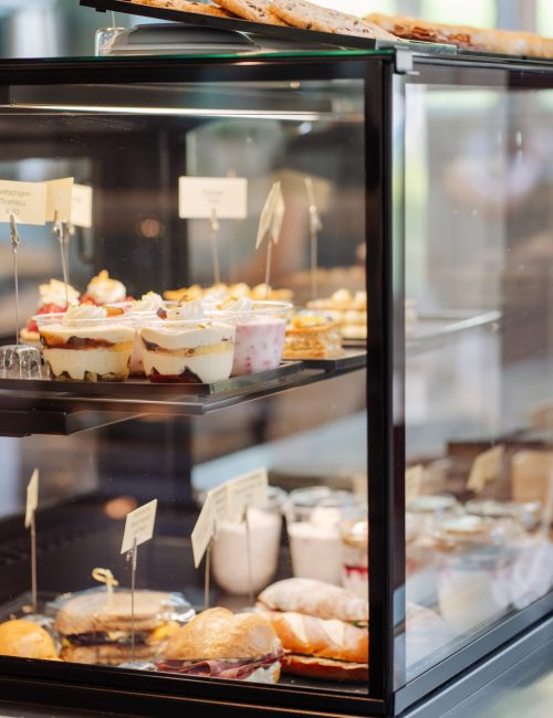 Vitrine gefüllt mit Patisserie, Sandwiches, Birchermüesli und Granola mit Joghurt und Früchten