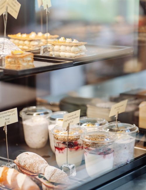 Vitrine gefüllt mit Patisserie, Sandwiches, Birchermüesli und Granola mit Joghurt und Früchten